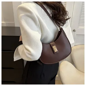 Rear view of model wearing a dark brown leather half-moon shoulder bag with gold buckle