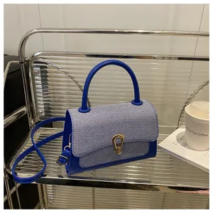 Detailed view of blue striped crossbody bag with gold lock on transparent shelf