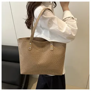 Close-up of woven texture large tote bag with metallic rivet details on handle