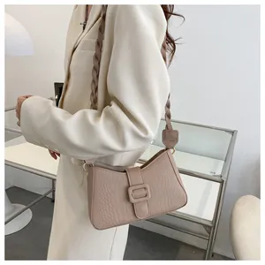 Detail of beige faux crocodile leather shoulder bag with a unique woven strap design
