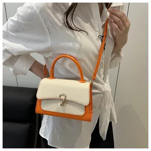 Close-up of stylish orange and cream patchwork handbag with elegant metal buckle detail