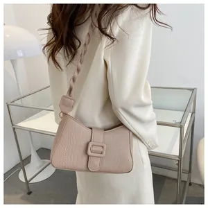 Detail of light pink crocodile pattern handbag featuring a unique woven braided strap