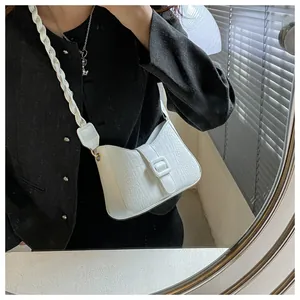Close-up of white crocodile pattern crossbody bag with woven strap and square buckle