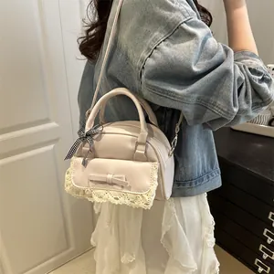 Elegant lace-stitched crossbody handbag with bow detail shown on a model for style