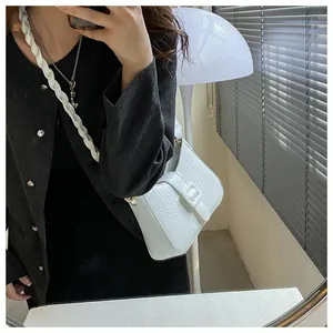 Detail of white crocodile pattern texture and twisted rope shoulder strap on a handbag