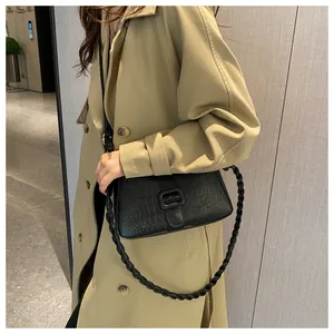 Detail of black crocodile embossed shoulder bag with unique spiral woven handle design