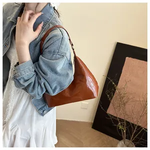 Brown patent leather hobo bag styled on shoulder with vintage denim jacket and lace dress