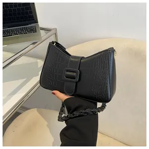 Detail of black crocodile embossed handbag featuring a unique twisted braided shoulder strap