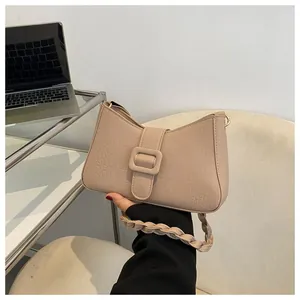 Detail of apricot crocodile pattern shoulder bag with woven strap and square buckle