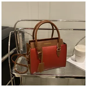 Detail of burgundy and brown crossbody bag featuring golden Fashion & Bags logo