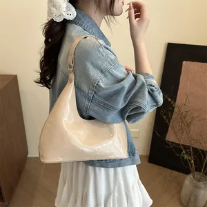 Glossy beige crescent underarm bag styled with a denim jacket and white skirt