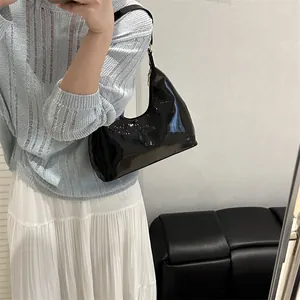 Glossy black patent leather hobo shoulder bag with a sleek minimalist embossed logo