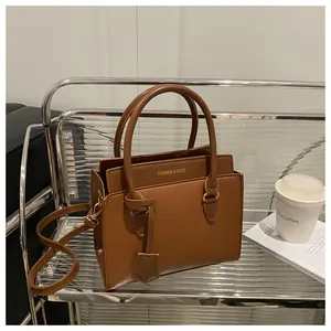 Detail of brown litchi leather tote bag with gold logo and adjustable shoulder strap