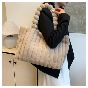 Detail of plush tote bag with vertical stripes and fluffy pom-pom handle in beige
