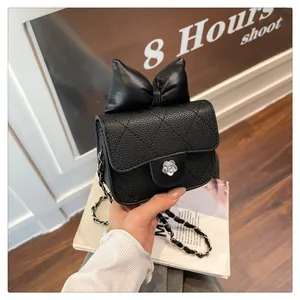 Detail of a black quilted mini crossbody bag with a large bow and flower clasp