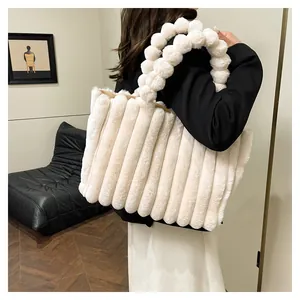 Detail of cream plush tote bag with unique pleated texture and soft faux fur pom-pom handle