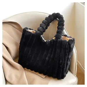 Detail of black plush tote bag featuring a unique fluffy ball handle on leather sofa