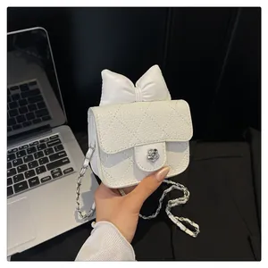 Detail of white mini crossbody bag featuring a large bow and silver flower clasp