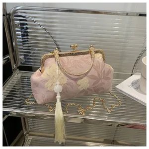 Detail of pink floral embroidery, kiss-lock closure and white tassel on luxury shell bag