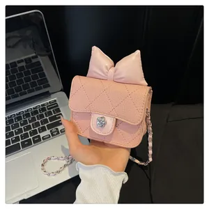 Detailed shot of pink quilted crossbody bag with leather bow and camellia metal clasp