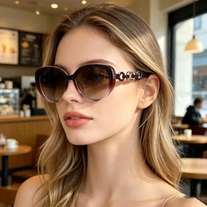 Close-up of cat-eye sunglasses with gradient lenses and decorative metal chain temple detail