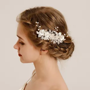 Close-up of bridal hair comb with handmade white flowers, silver leaves, and pearls