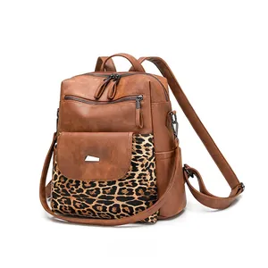 Detail view of brown pebbled leather backpack with leopard print pocket and dual zippers