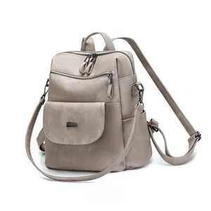 Detail view of taupe faux leather backpack with metallic zippers and adjustable straps