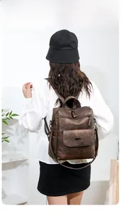 Rear view of a vintage brown PU leather backpack with multiple zipper pockets on a model