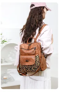 Detail of vintage brown PU leather backpack with leopard print pocket on white dress