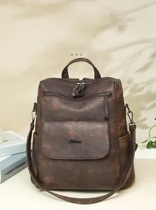 Detail of vintage brown leather backpack with textured finish and silver hardware