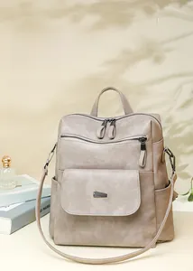 Detail of taupe faux leather backpack featuring metal buckles and organized zipper pockets