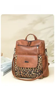 Detail view of brown PU leather backpack with leopard print pocket and metal zipper details