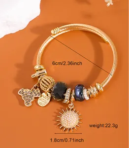 Close-up of gold beaded bracelet with bear and sunflower charms and size dimensions