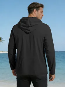 Rear view of a black hooded cotton linen shirt showing its loose fit and texture on a beach