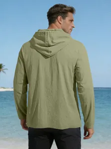 Back view of a men's light green hooded cotton shirt on a sunny beach setting