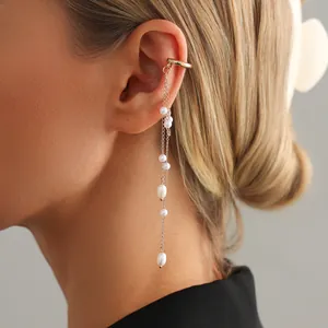 Detail of elegant gold ear cuff with long flowing chains and white baroque pearls