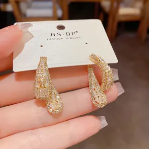 Vue détaillée de boucles d'oreilles pendantes en zircone avec finition dorée.