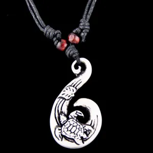 Close-up of Maori fish hook pendant with turtle totem and black woven cord