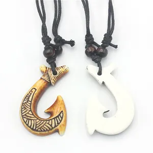 Close-up of Maori style resin fish hook pendants with tribal patterns and wooden beads
