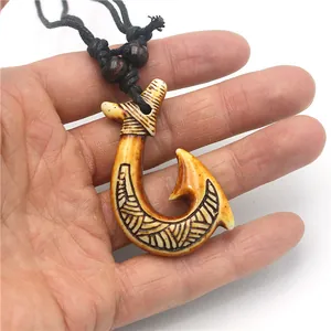 Detail of Maori style resin fish hook pendant with tribal carvings and black cord