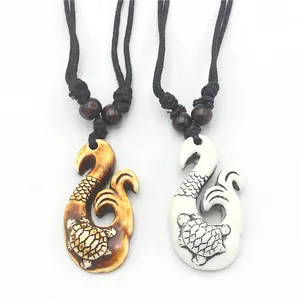 Detail view of Maori style fish hook pendants with turtle carving and black cord
