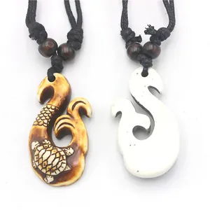 Detail of Maori Hei Matau fish hook resin pendants with turtle engraving and woven cords