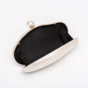 Detail view of the shell-shaped acrylic clutch bag with marble texture and pearl clasp