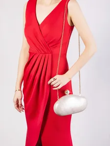 Detail of ivory shell acrylic clutch with large pearl clasp on red evening dress
