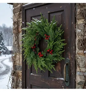 Künstlicher Weihnachtskranz mit roten Beeren und Zapfen an einer dunklen Holztür.