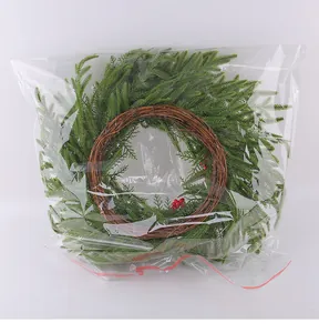 Künstlicher Weihnachtskranz aus Kiefernnadeln mit roten Beeren in Plastiktüte