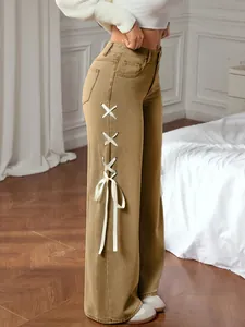 Detail of wide white ribbons with metal eyelets on khaki wide-leg jeans side