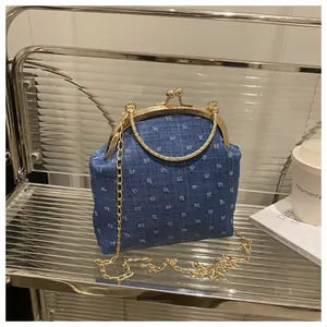 Dettaglio borsa a conchiglia in denim blu con telaio dorato e manico circolare in metallo