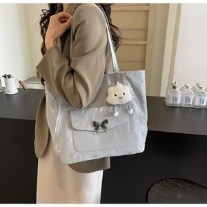 Detail of silver tote bag featuring pleated texture and metallic butterfly buckle lock